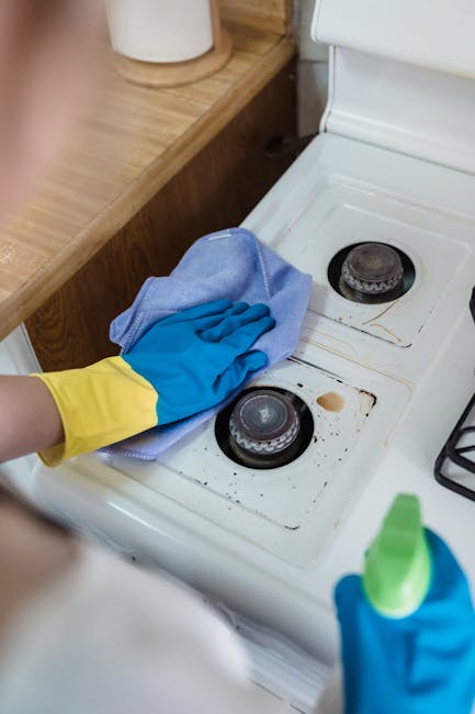 Close-up view of a modern stainless steel oven with a control panel featuring digital and manual buttons, situated in a kitchen with wooden flooring. The oven door is closed, displaying a smooth metal